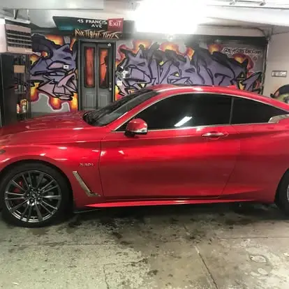 Red Infiniti Q60 with tinted windows inside the shop